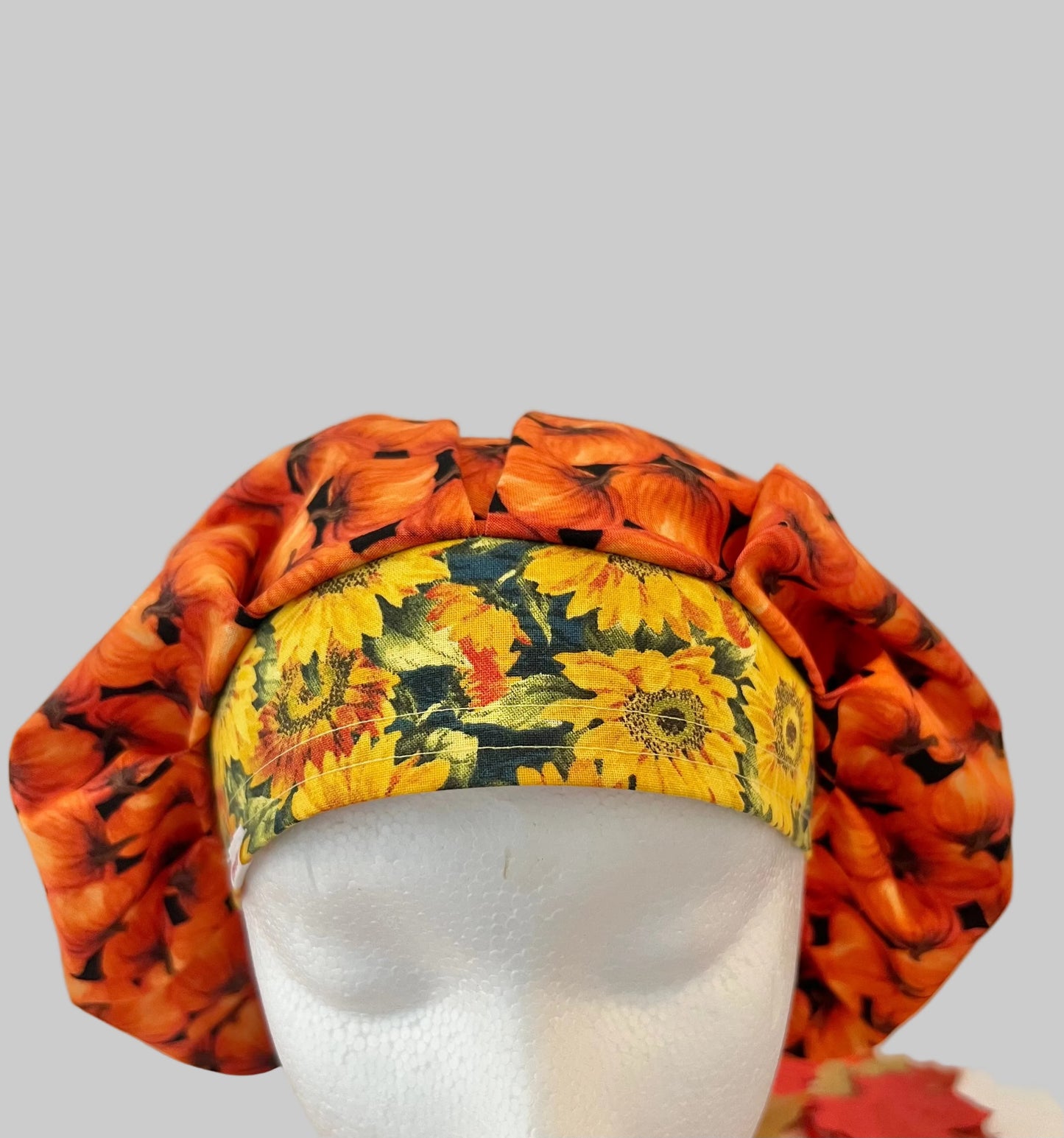 Fall pumpkin bouffant scrub cap for women, front view with yellow sunflower band, autumn surgical hat, OR World