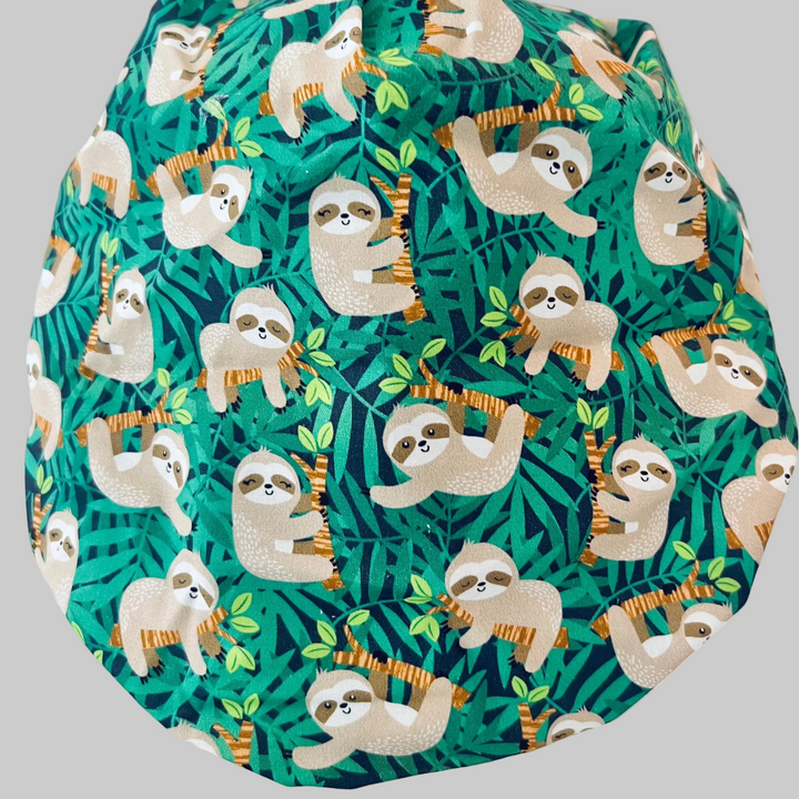 Cute Sloth Euro Scrub Cap featuring tropical jungle leaves. Adjustable unisex OR cap with optional satin lining available. Perfect gift for nurses, surgeons, veterinarians, surgical techs, and healthcare workers.