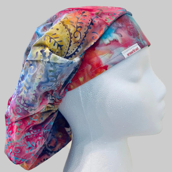 Pastel candyland batik bouffant scrub cap in pink, blue &amp; lavender, on a model — handmade-in-USA surgical hat for women from OR World.