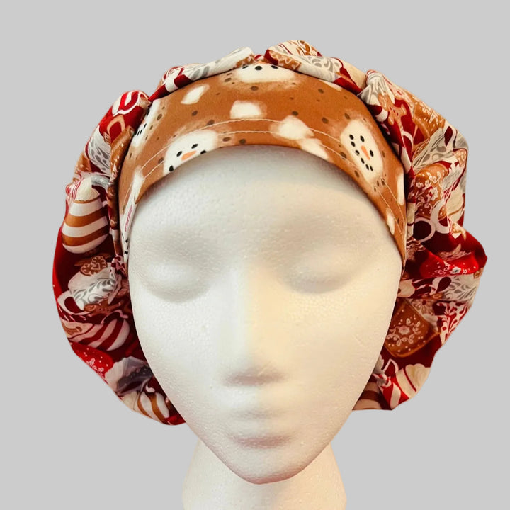 Christmas hot chocolate and marshmallow bouffant scrub cap with festive cocoa mugs, peppermint, gingerbread cookies, marshmallows, snowflakes, and snowman band for nurses, surgeons, dietitians, and medical professionals, front view.