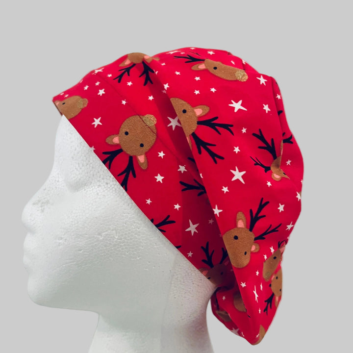 Christmas reindeer euro scrub cap with adorable brown reindeer faces on a festive red background with white stars, handmade unisex surgical cap for nurses, surgeons, dental professionals, veterinarians, medical staff, holiday scrub hat gift, left side view