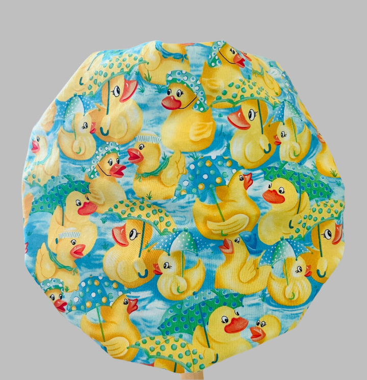 Back view of rubber duckies &amp; rain boots bouffant scrub cap — handmade-in-USA OR World aqua surgical hat for women with long hair.