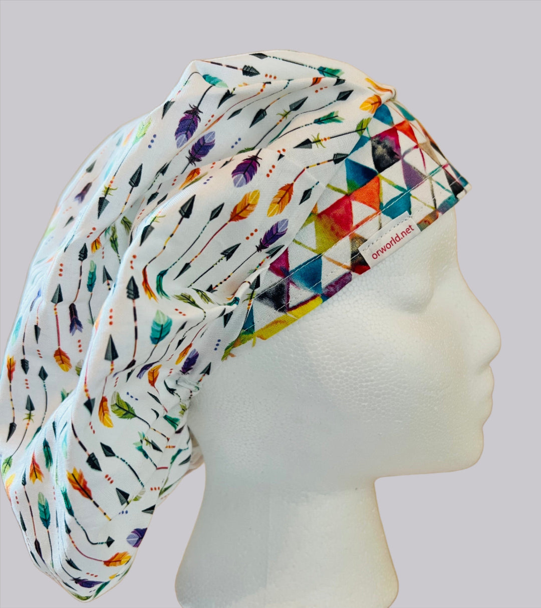 White bouffant scrub cap with colorful arrows in purple, orange, aqua &amp; green on a model — handmade-in-USA surgical hat for women from OR World.