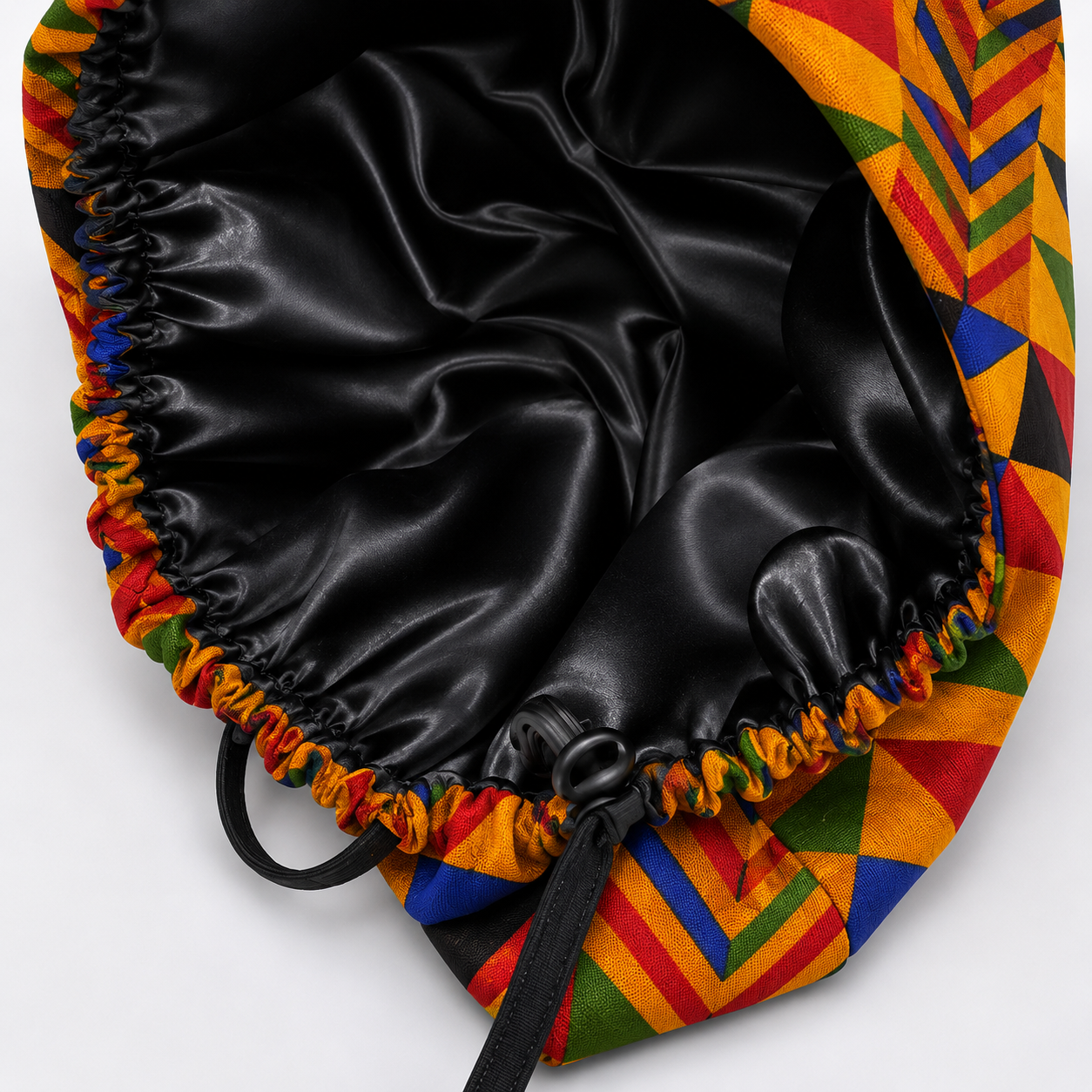 Colorful Geometric African Kente bouffant scrub cap flat lay showing black satin lining interior bold Ghana triangle pattern surgical hat handmade USA