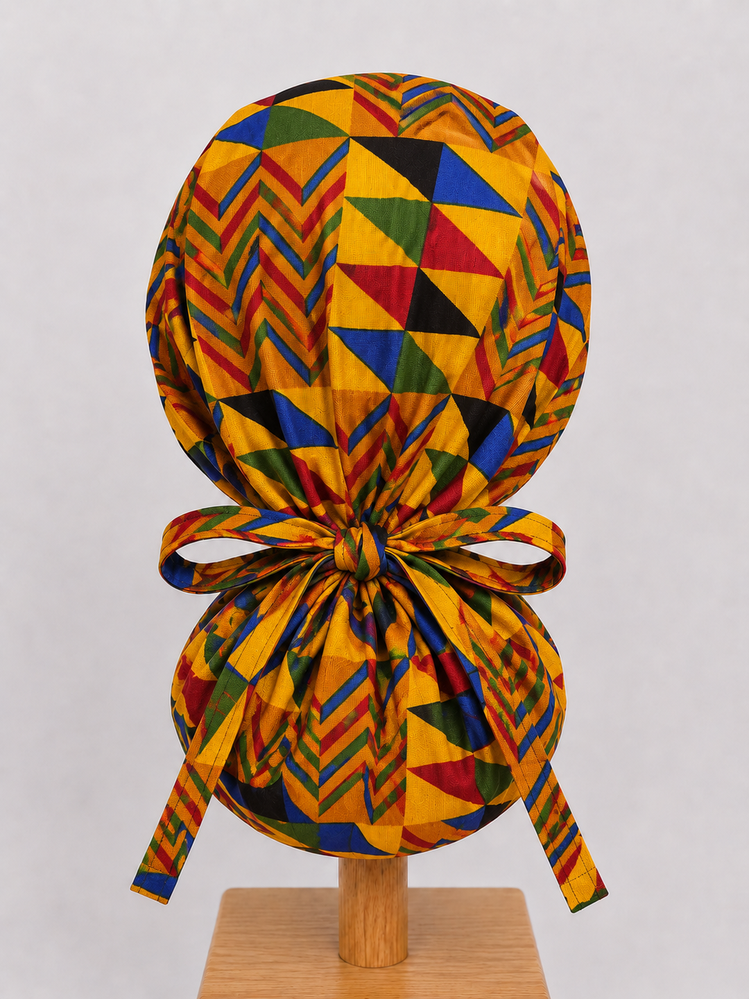 Colorful Geometric African Kente ponytail scrub cap back view showing tie closure bold gold blue red green Ghana Kente triangle print surgical hat handmade USA
