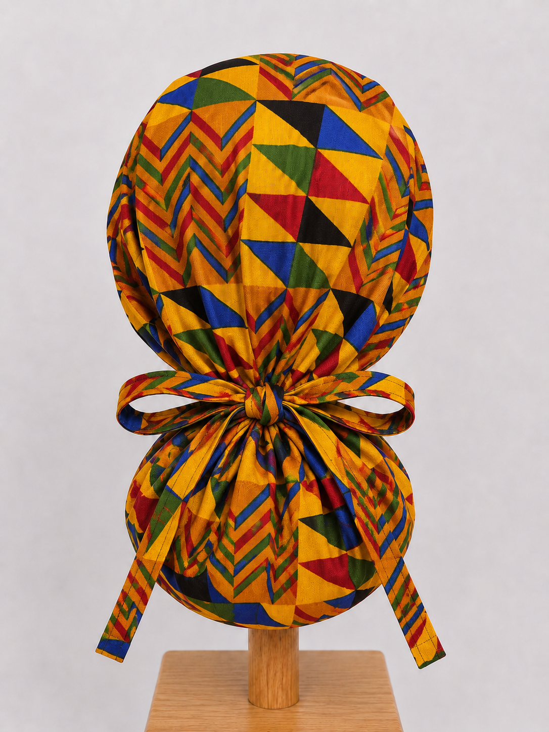 Colorful Geometric African Kente ponytail scrub cap back view showing tie closure bold gold blue red green Ghana Kente triangle print surgical hat handmade USA