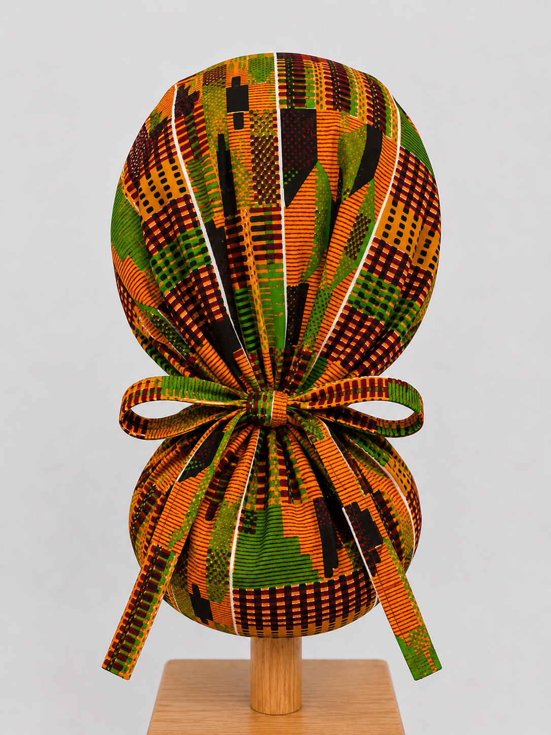 African Kente Ghana original ponytail scrub cap back view showing tie closure traditional orange green brown black Kente print surgical hat handmade USA OR World