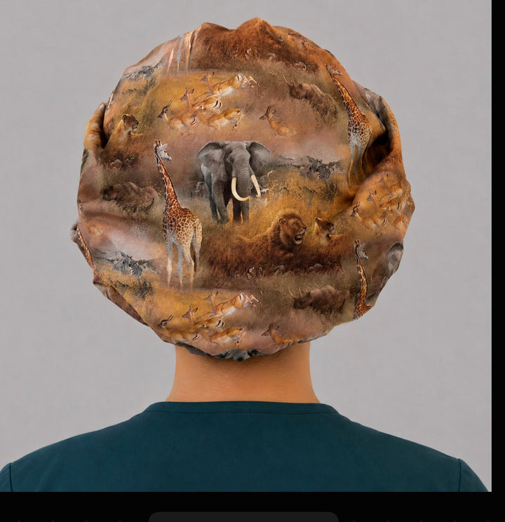African safari bouffant scrub cap back view showing full savanna scene of elephant, lion, giraffe and zebra on golden grassland, OR World