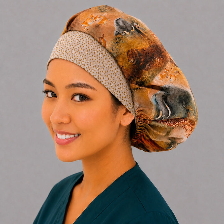 African safari wildlife bouffant scrub cap left three-quarter angle on smiling model showing elephant, buffalo and giraffe savanna print with gold dot band, OR World
