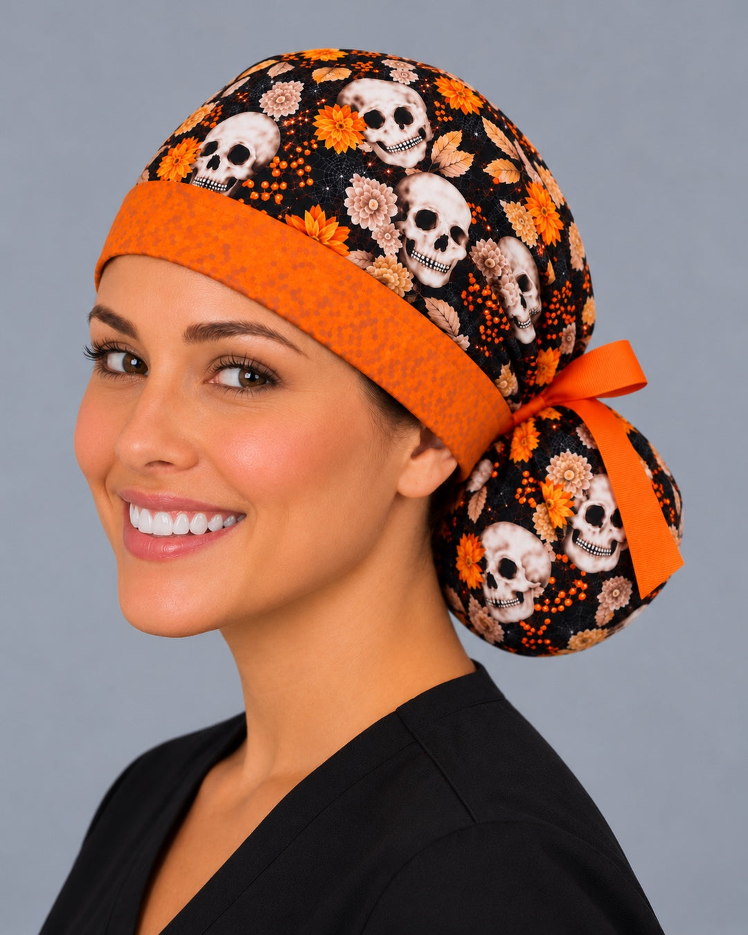 Three-quarter angle of a smiling healthcare worker in an autumn skull scrub hat, with orange berries and fine spiderwebs shown at true print scale