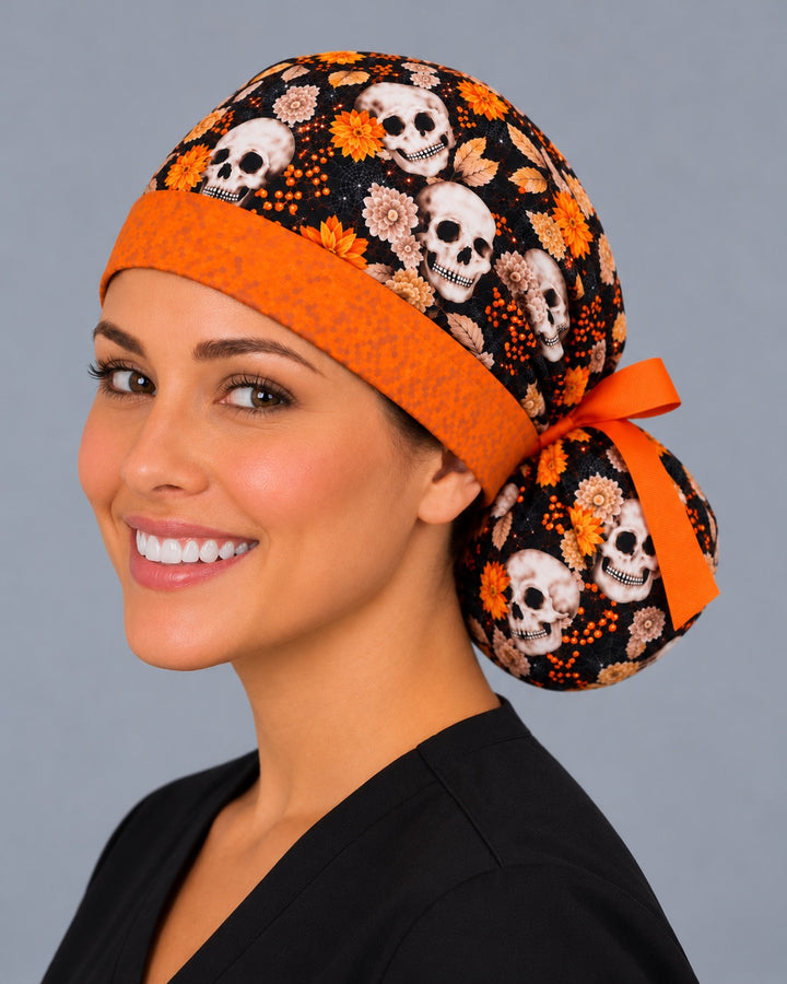Three-quarter angle of a smiling healthcare worker in an autumn skull scrub hat, with orange berries and fine spiderwebs shown at true print scale