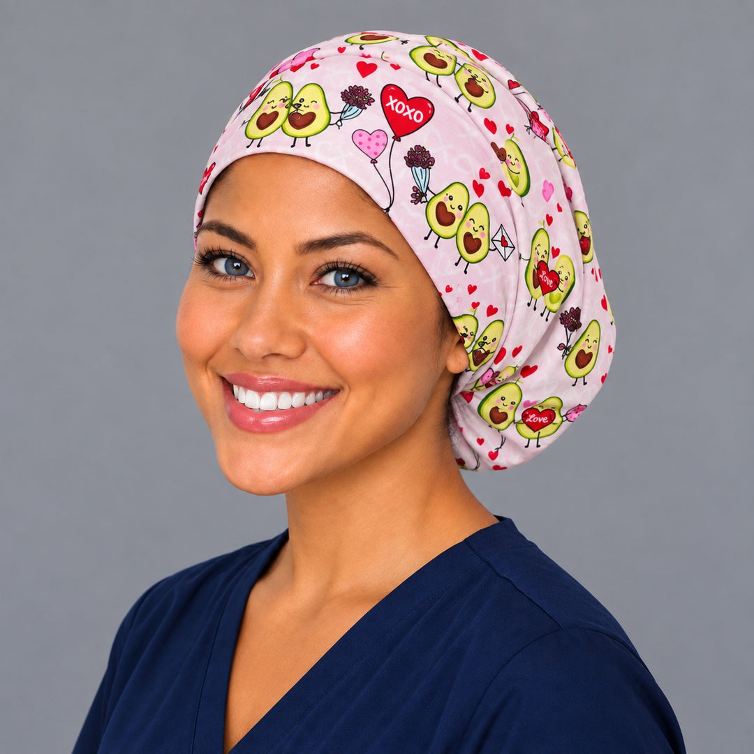 Woman wearing an Avocado Love Euro scrub cap, front view — smiling avocado couples and hearts on pink, adjustable Valentine's surgical hat