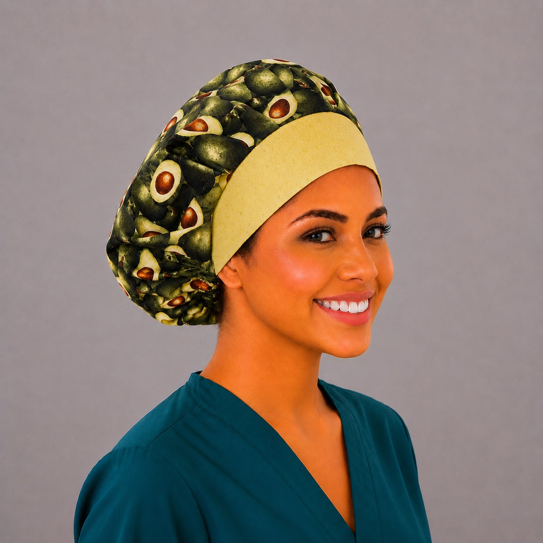 Avocado print bouffant scrub cap left three-quarter angle on smiling model showing whole and halved avocados with yellow band, women&