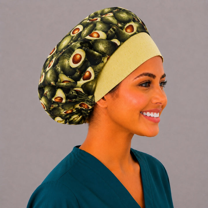 Avocado print bouffant scrub cap right side profile on smiling model showing whole and halved avocados with yellow band, women&