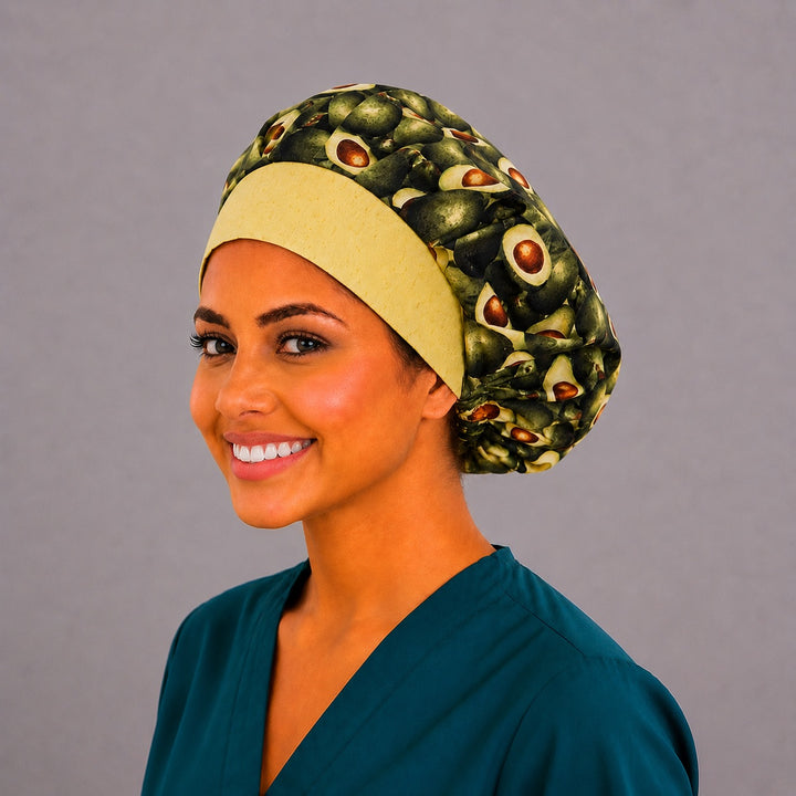 Avocado print bouffant scrub cap right three-quarter angle on smiling model showing halved avocados with buttery-yellow band, OR World foodie nurse hat