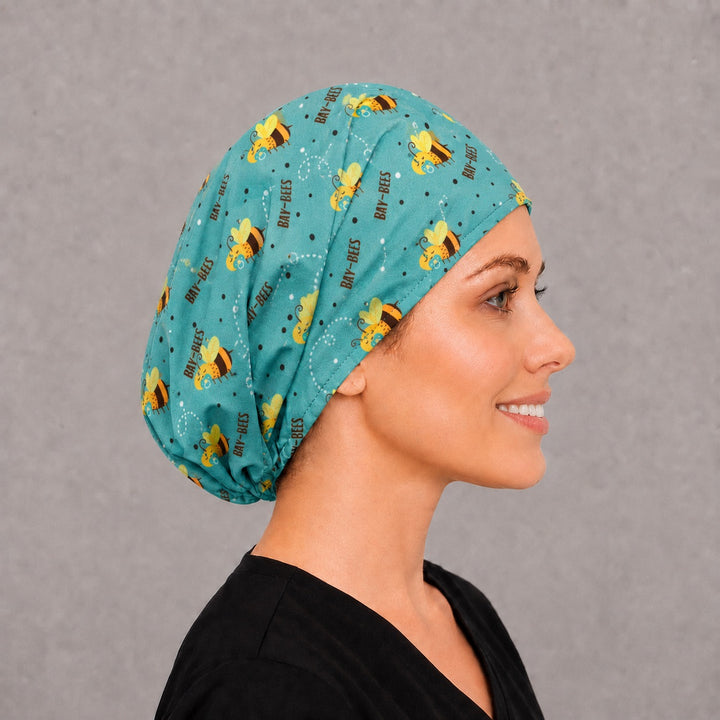 Back view of the baby bee Euro scrub cap — full coverage showing Bay-Bees lettering and pacifier bees across the teal crown