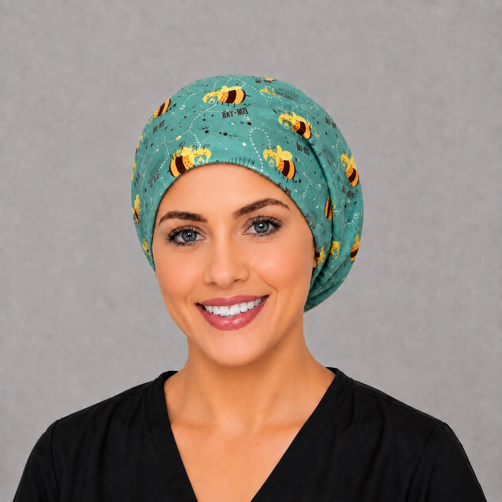 Woman wearing a baby bee Euro scrub cap, front view — sleeping Bay-Bees with pacifiers on teal, adjustable L&D surgical hat