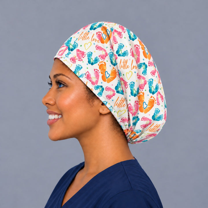 Left side profile of a baby footprint OR cap in 100% cotton, showing the adjustable elastic back and a deep crown with room for long hair or a bun