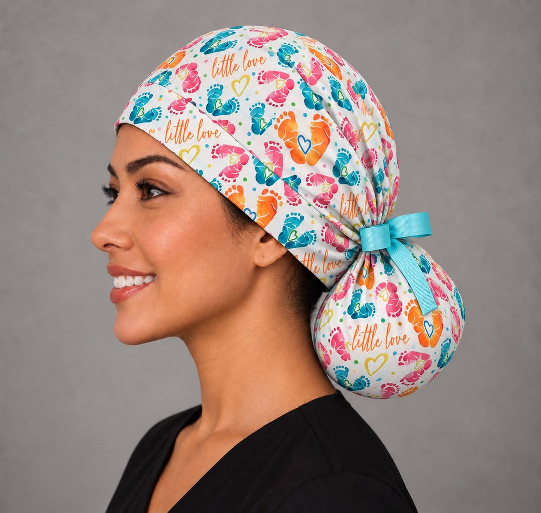 Left profile of a baby footprint ponytail OR cap in 100% cotton, showing the smooth forehead band and a round bun pouch holding long hair