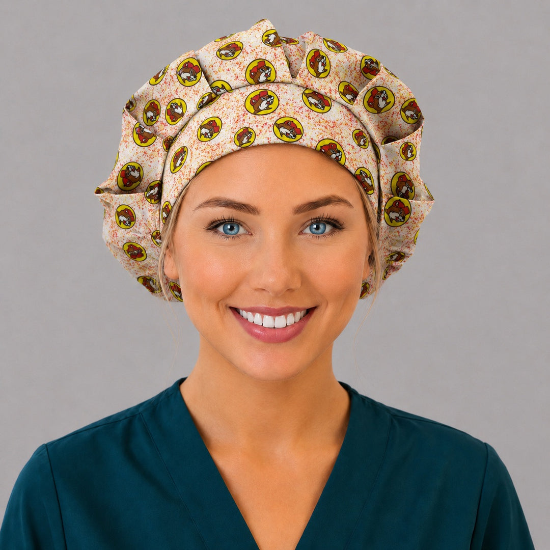 Beaver print bouffant surgical cap right three-quarter angle on smiling model, red and yellow beaver mascot badges on cream, OR World funny nurse hat