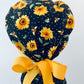 Back view of Bee Grateful sunflower ponytail scrub cap with yellow bow and ponytail pouch — handmade-in-USA OR World surgical hat for long hair.