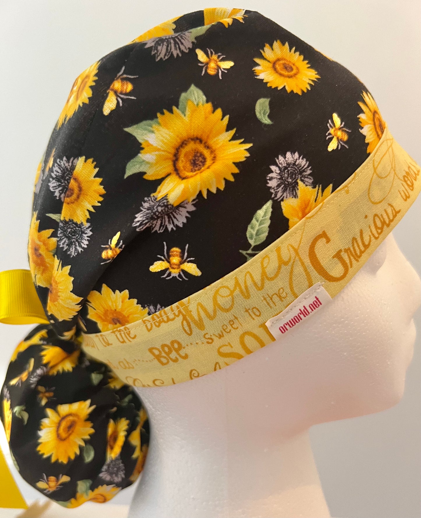 Side view of Bee Grateful sunflower bee ponytail scrub cap with back pouch & bow — handmade USA surgical hat for OR nurses with long hair.
