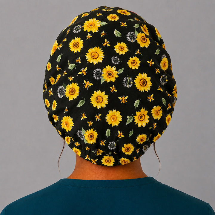 Bee Grateful sunflower bouffant scrub cap back view showing full print of golden sunflowers and honeybees on black, OR World surgical hat