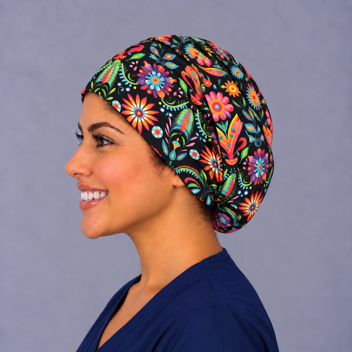Right profile of a black folk floral euro surgical cap, showing the rounded elastic back gathered low at the nape behind the ear