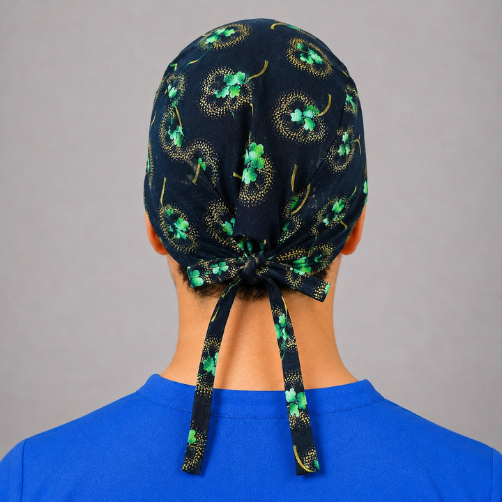 Black and gold shamrock scrub cap for short hair, handmade four-leaf clover tie-back surgical hat on OR nurse, front view