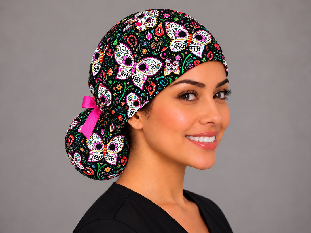Three-quarter view of the black paisley sugar skull ponytail nurse cap on a smiling OR nurse, low bun held in the printed pouch