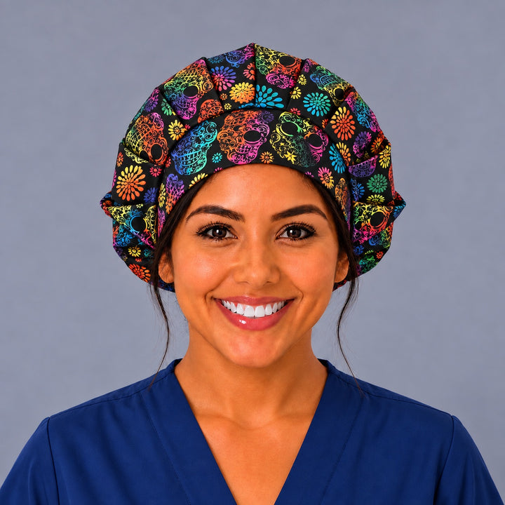 Nurse wearing a black rainbow calavera bouffant surgical hat, front view, pleated full crown with lacy rainbow skulls