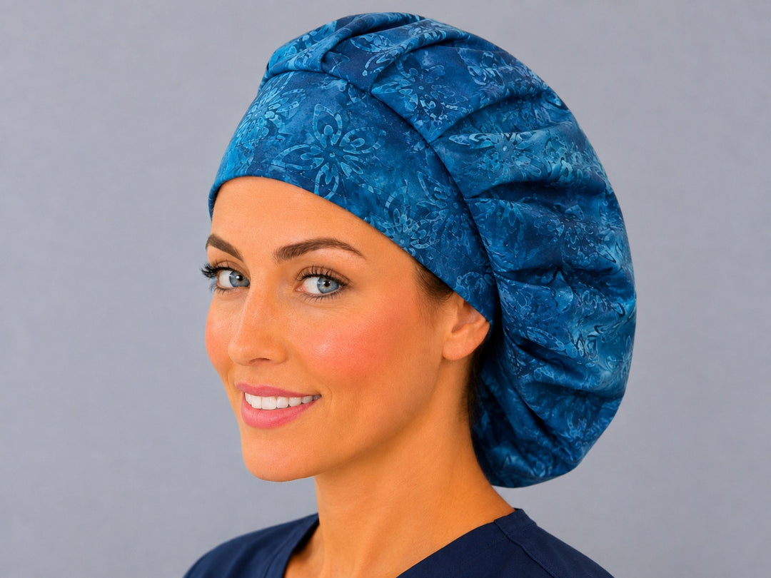 Woman wearing a blue batik floral bouffant scrub cap, angled view — midnight and cobalt batik flower print, adjustable women's surgical hat