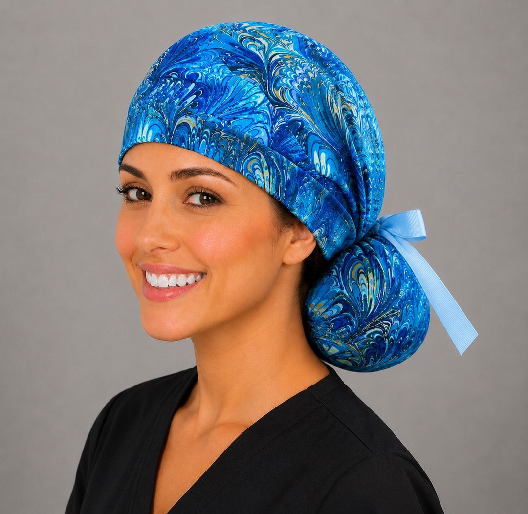 Blue marble ocean swirl ponytail nurse cap right three-quarter angle showing blue and gold marbled swirl print and light blue ribbon bow