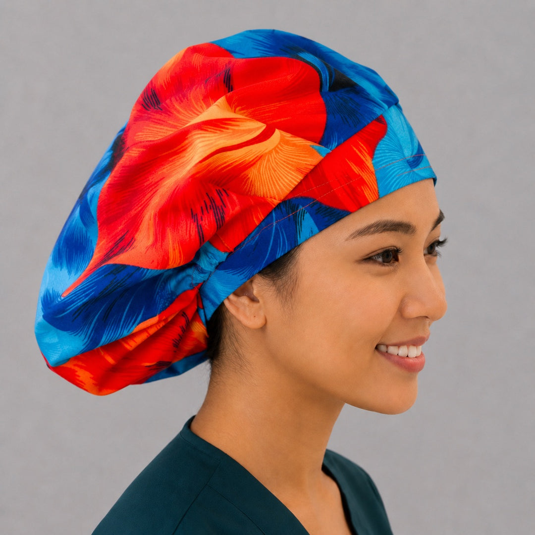 Blue and orange Hawaiian hibiscus bouffant scrub cap left three-quarter angle on smiling model showing blue red and orange hibiscus flowers, OR World tropical nurse hat