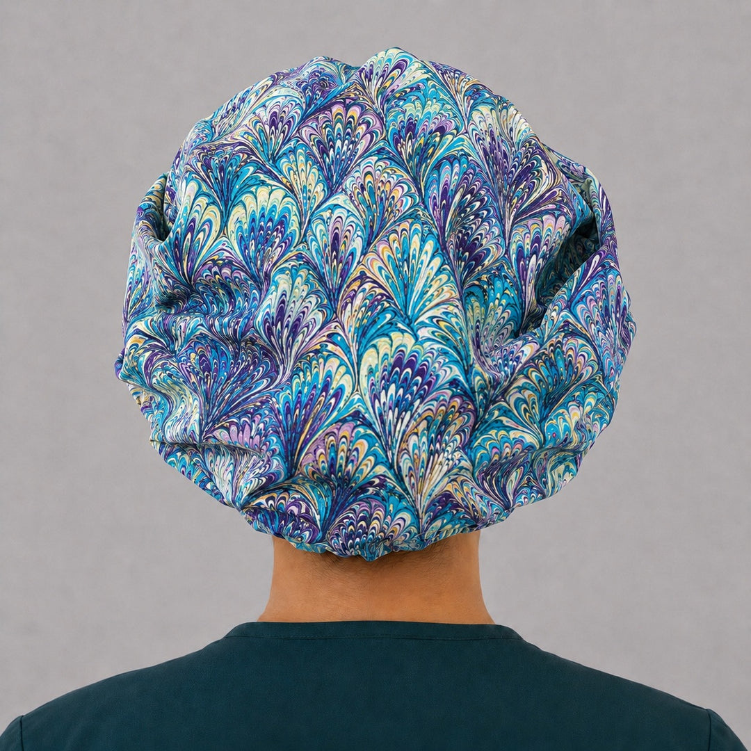 Blue and purple ripples bouffant surgical cap right three-quarter angle on smiling model, marbled turquoise and purple swirl print, OR World nurse hat