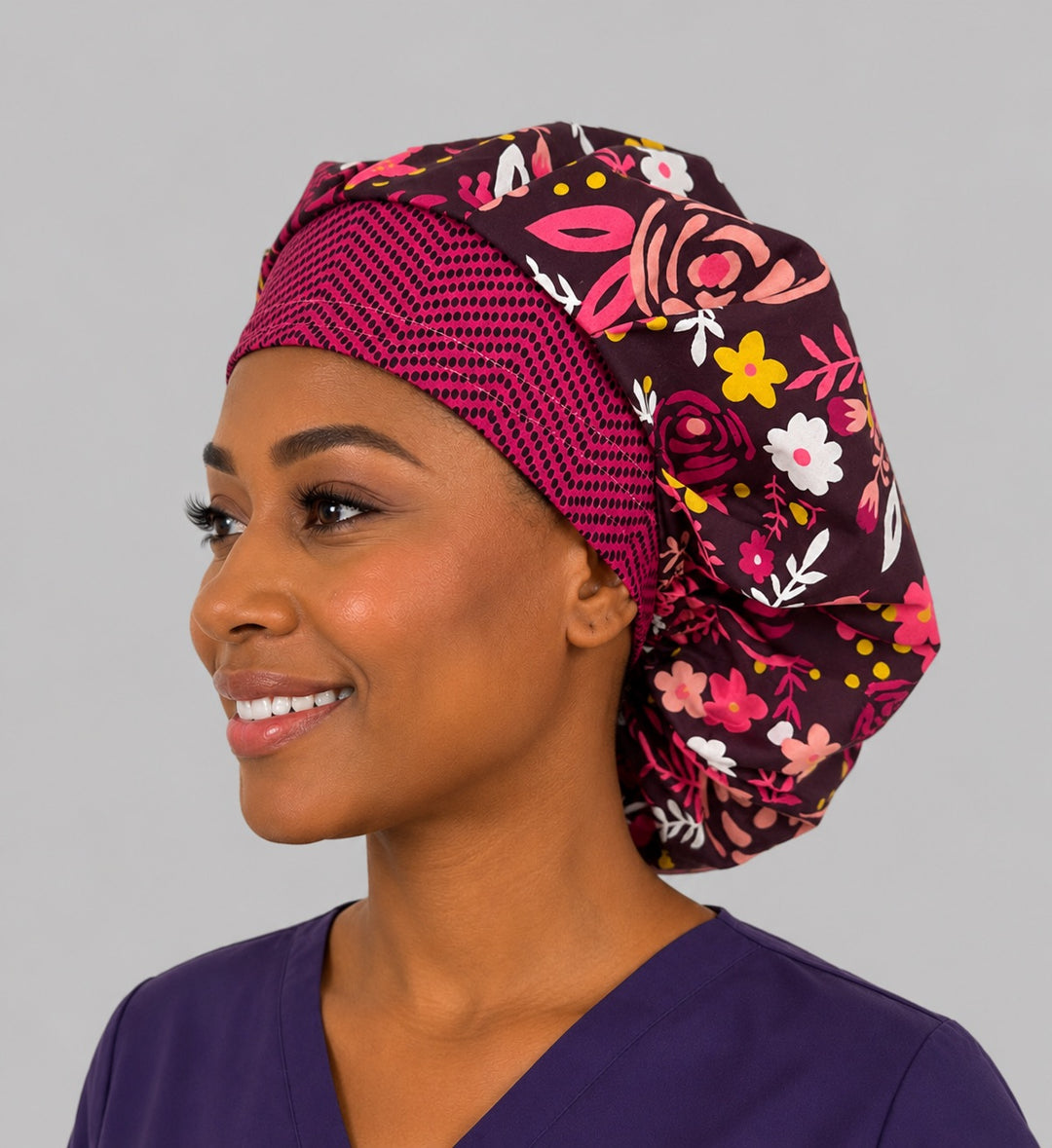 Angled view of the bold rose floral bouffant cap for women on a smiling L&amp;D nurse — handmade cotton surgical cap, USA made