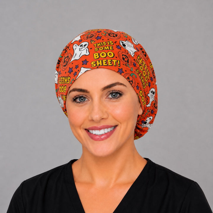Woman wearing a Boo Sheet ghost Euro scrub cap, front view — funny ghosts and pumpkins on orange, adjustable Halloween surgical hat
