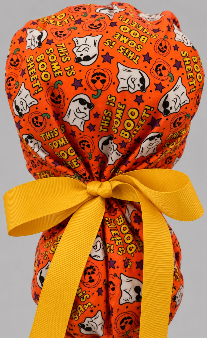 Back view of the Boo Sheet ponytail scrub cap — golden yellow grosgrain bow tied over the pouch with ghosts and lettering