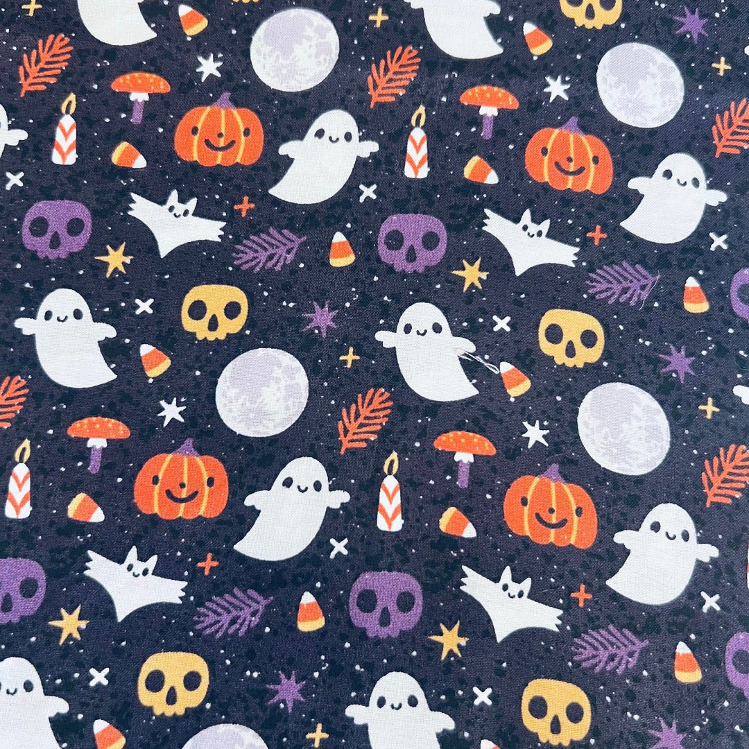 Fabric detail of the Boo-tiful Harvest scrub cap — close-up of ghosts, pumpkins, skulls and moons on navy cotton