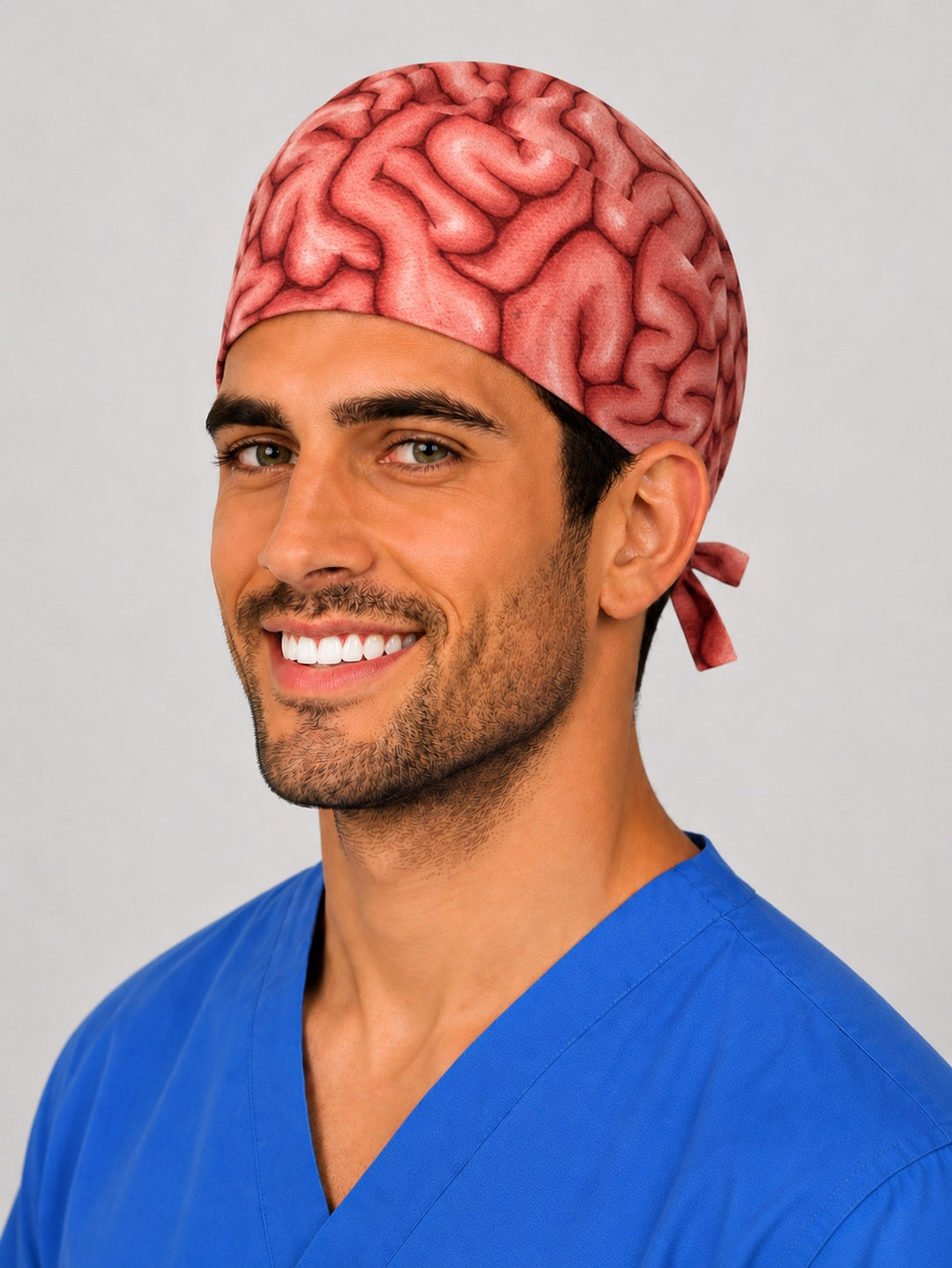 Brain anatomy neurosurgery scrub cap on a smiling male surgeon, front three-quarter angle showing the tie-back