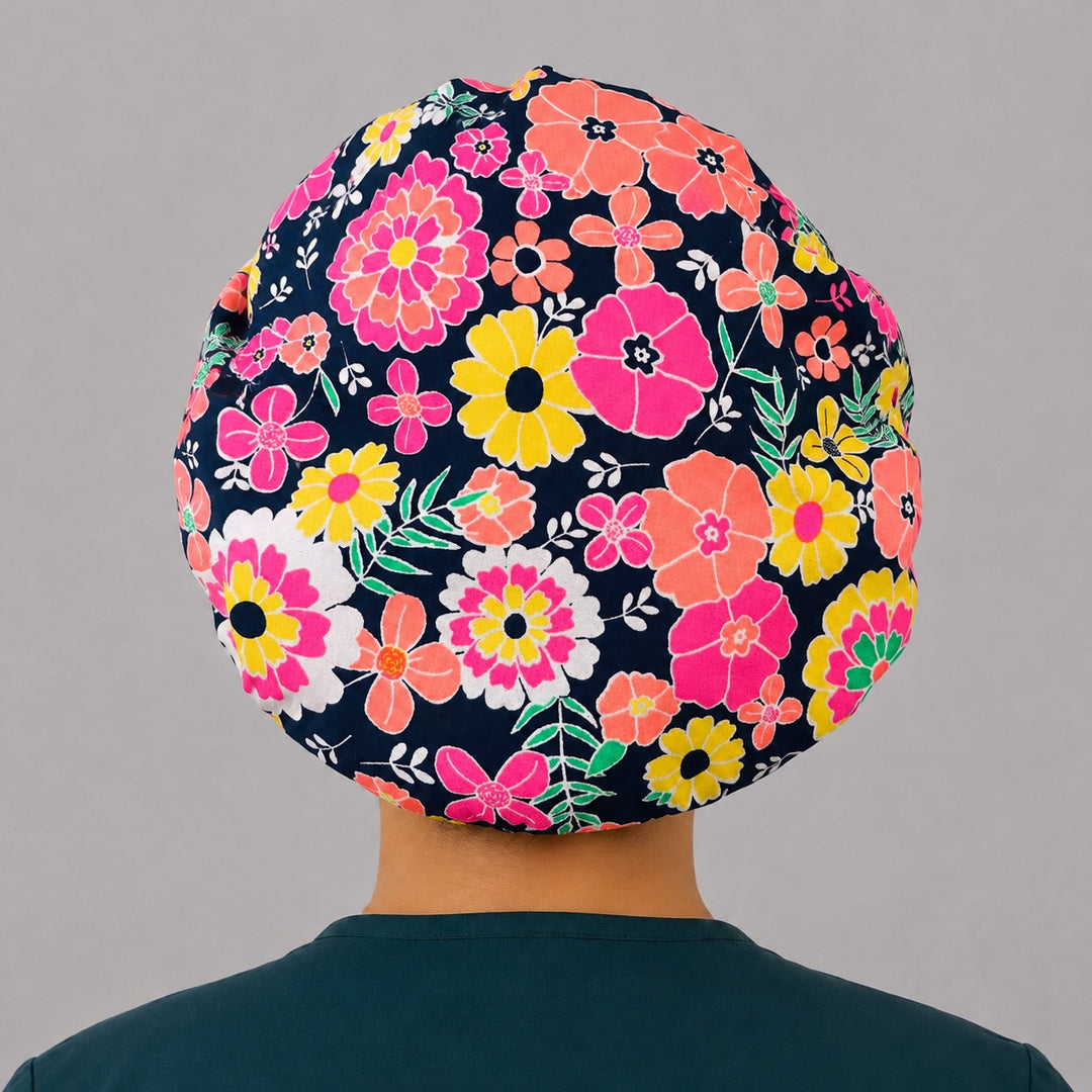 Bright floral neon flower bouffant scrub cap back view showing full print of bold pink coral and yellow flowers on navy, OR World surgical hat