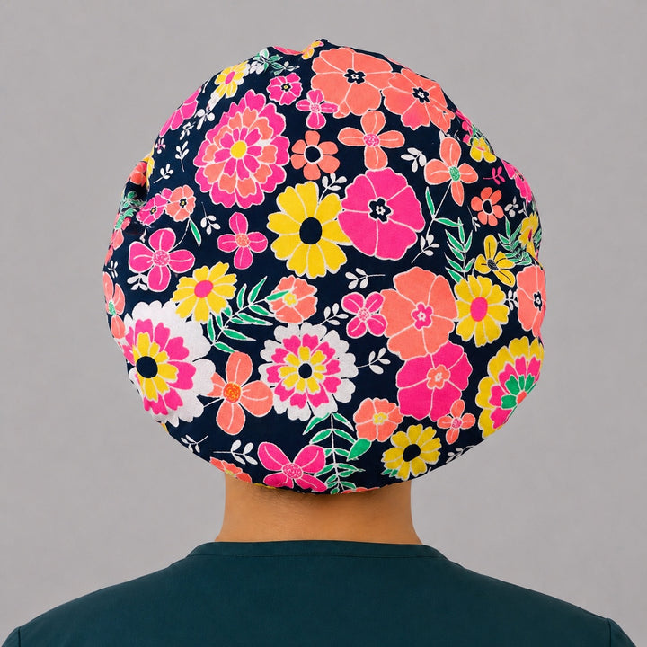 Bright floral neon flower bouffant scrub cap back view showing full print of bold pink coral and yellow flowers on navy, OR World surgical hat