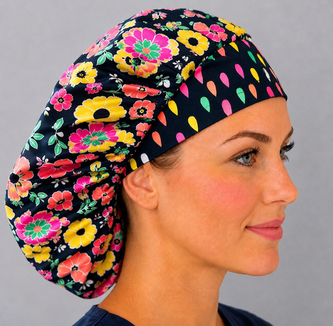 Bright floral neon flower bouffant scrub cap left three-quarter angle on smiling model, bold neon flowers on navy with confetti-dot band, women&