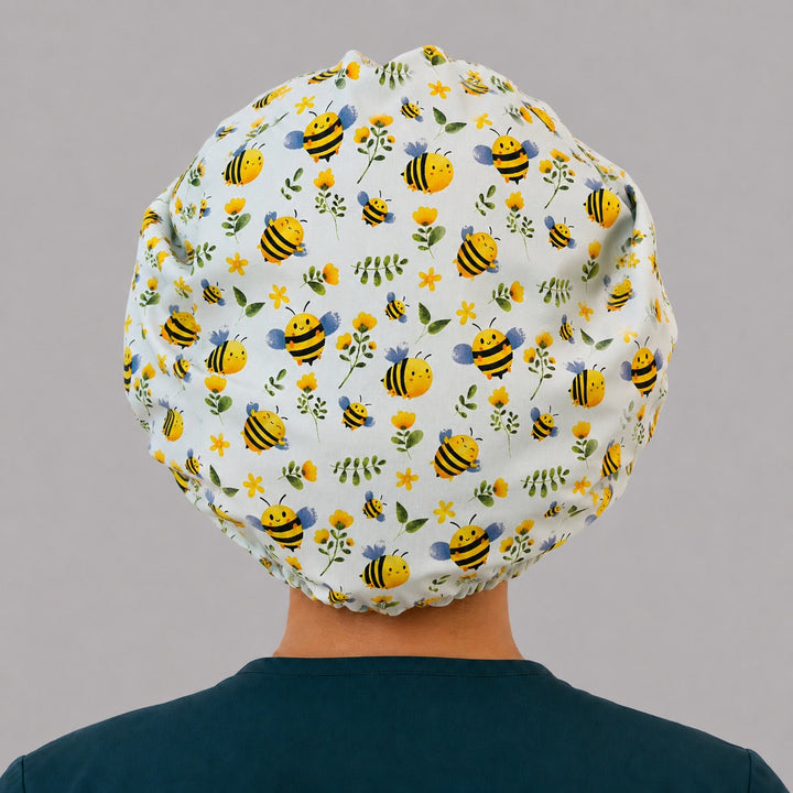 Side view of the bumblebee floral bouffant surgical hat — bee print with blue and white daisy band, roomy breathable cotton cap for nurses