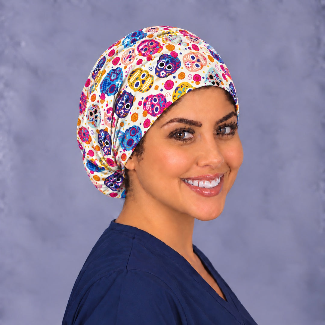 Right three-quarter angle of a calavera nurse scrub hat, showing violet and yellow skulls on the crown and soft folds over the back of the head