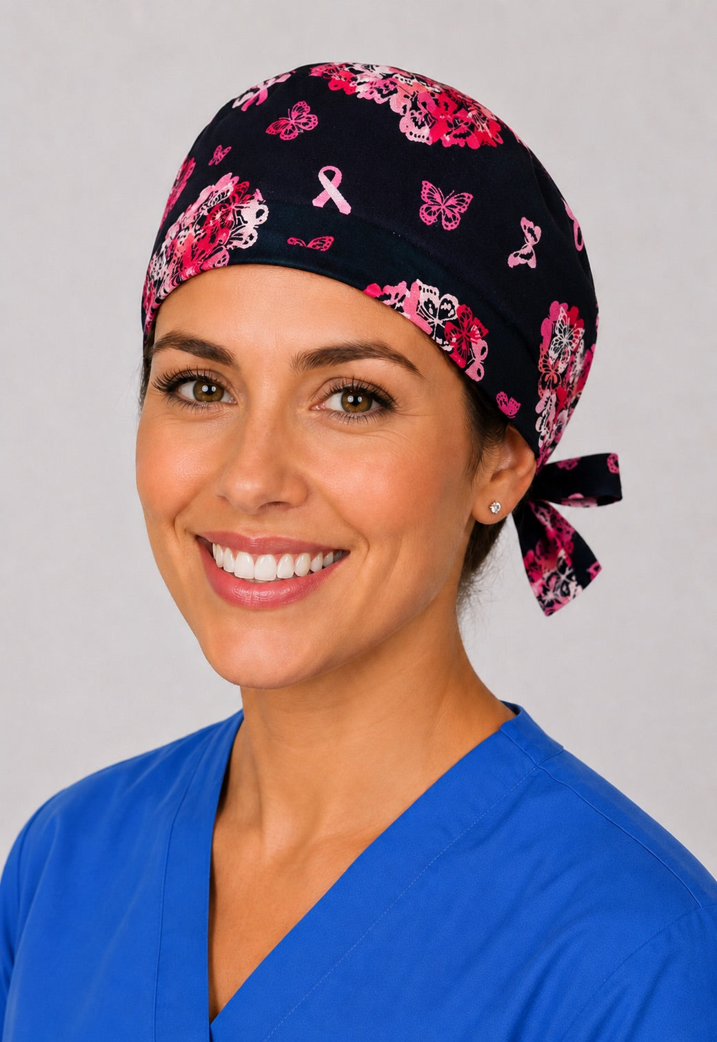 Cancer hearts scrub cap with pink butterfly hearts and awareness ribbons on black, handmade tie-back surgical hat for short hair on OR nurse, front view