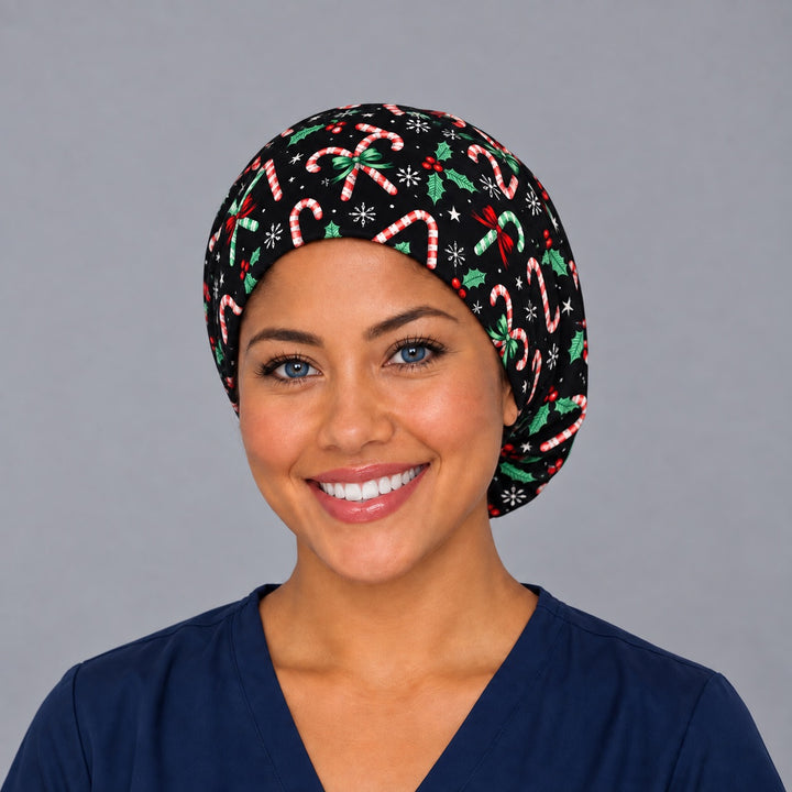 Woman wearing a Christmas candy cane Euro scrub cap, front view — candy canes, holly and snowflakes on black, adjustable holiday surgical hat