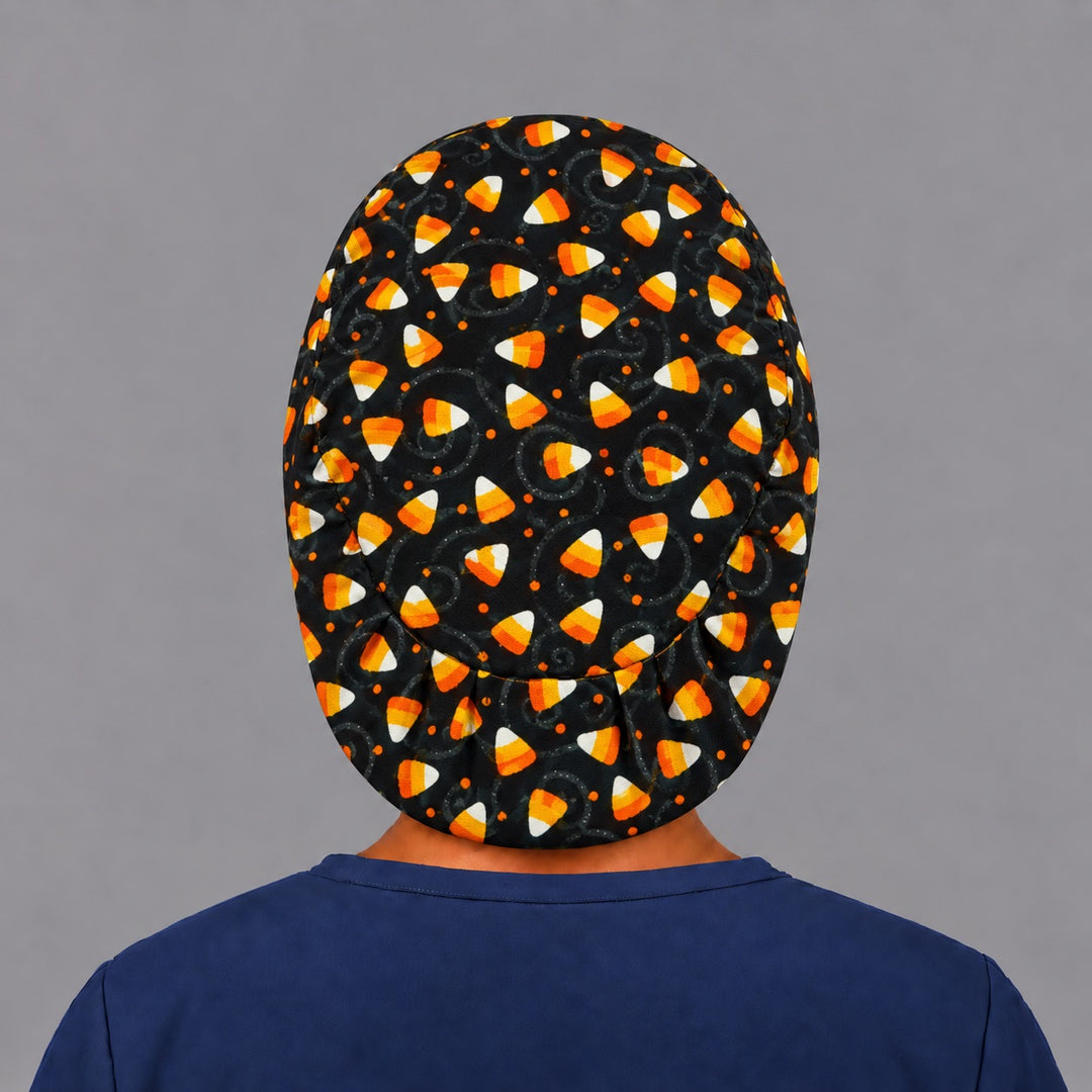 Full back view of the candy corn Euro scrub cap — flat lay showing candy corn and swirls on black