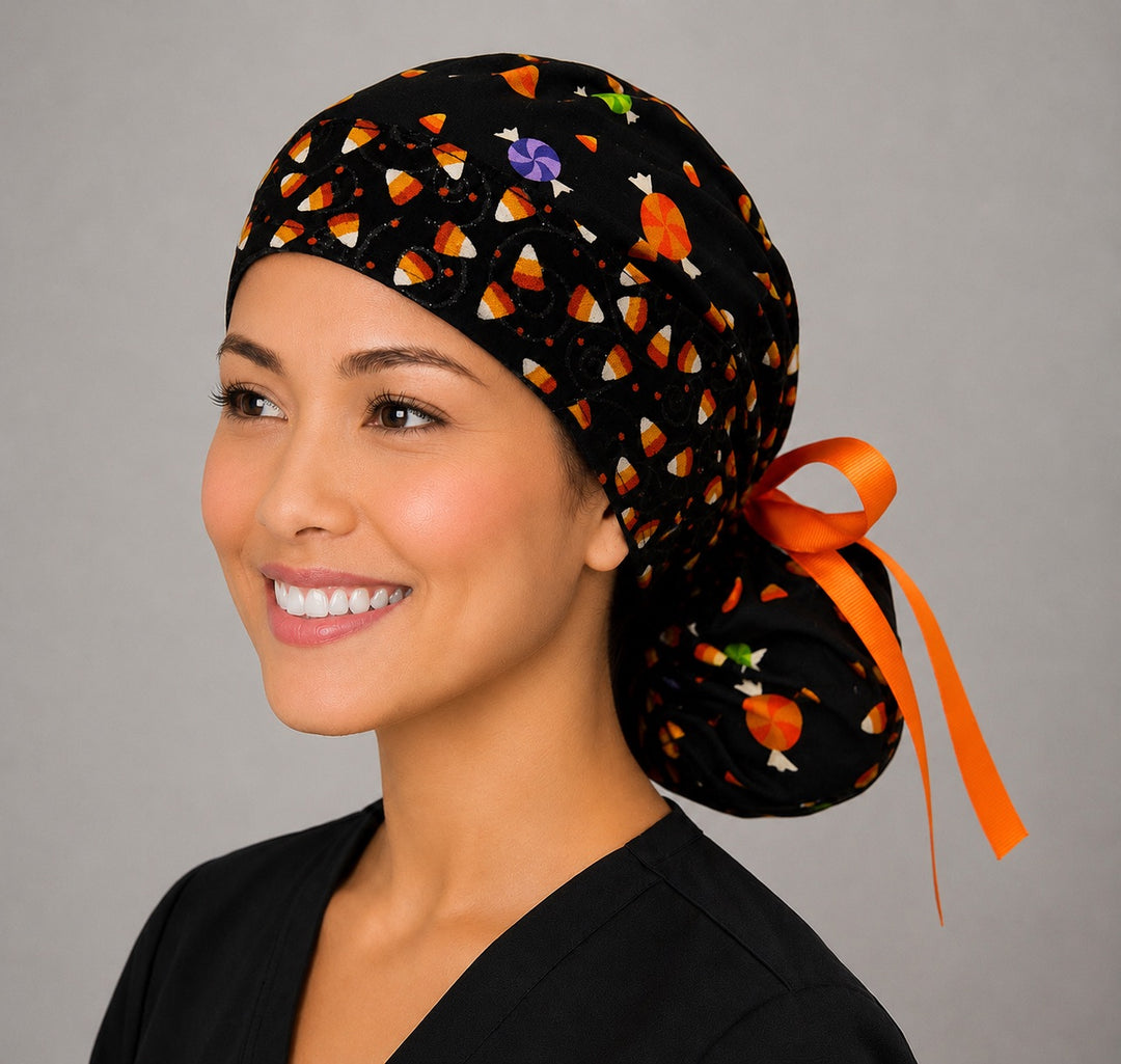 Halloween candy corn ponytail nurse cap front angle on smiling model showing candy corn and candy band with black glitter swirls and orange ribbon bow