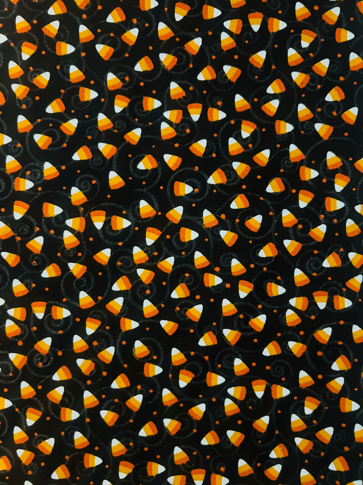 Fabric detail of the candy corn scrub cap — close-up of candy corn, swirls and dots on black cotton